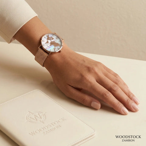 Women's rose gold watch with reflective metallic world map dial on mother of pearl background Woodstock Zambon worn on wrist