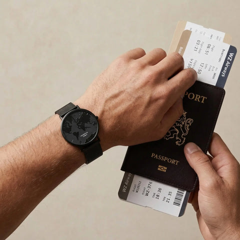 Men's waterproof watch with black reflective world map dial Woodstock Zambon worn on wrist holding passport and boarding passes