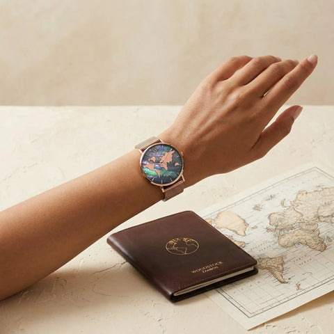 Women's waterproof 18K gold plated watch with reflective world map dial on mother of pearl background Woodstock Zambon worn on wrist