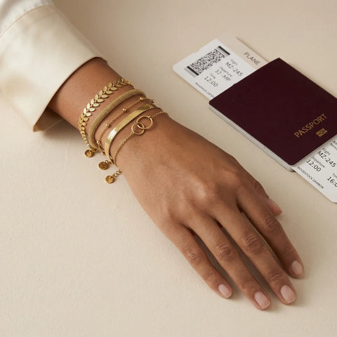 woman wearing layered gold bracelets set, elegant minimal stack jewelry on wrist, Woodstock Zambon