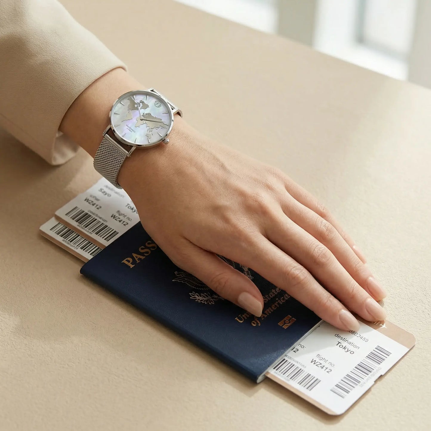 Elegant women's watch with mother of pearl world map dial Woodstock Zambon worn on wrist over passport and boarding pass