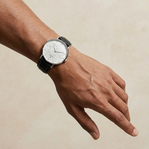 Men's white minimalist world map watch with black leather strap by Woodstock Zambon worn on wrist