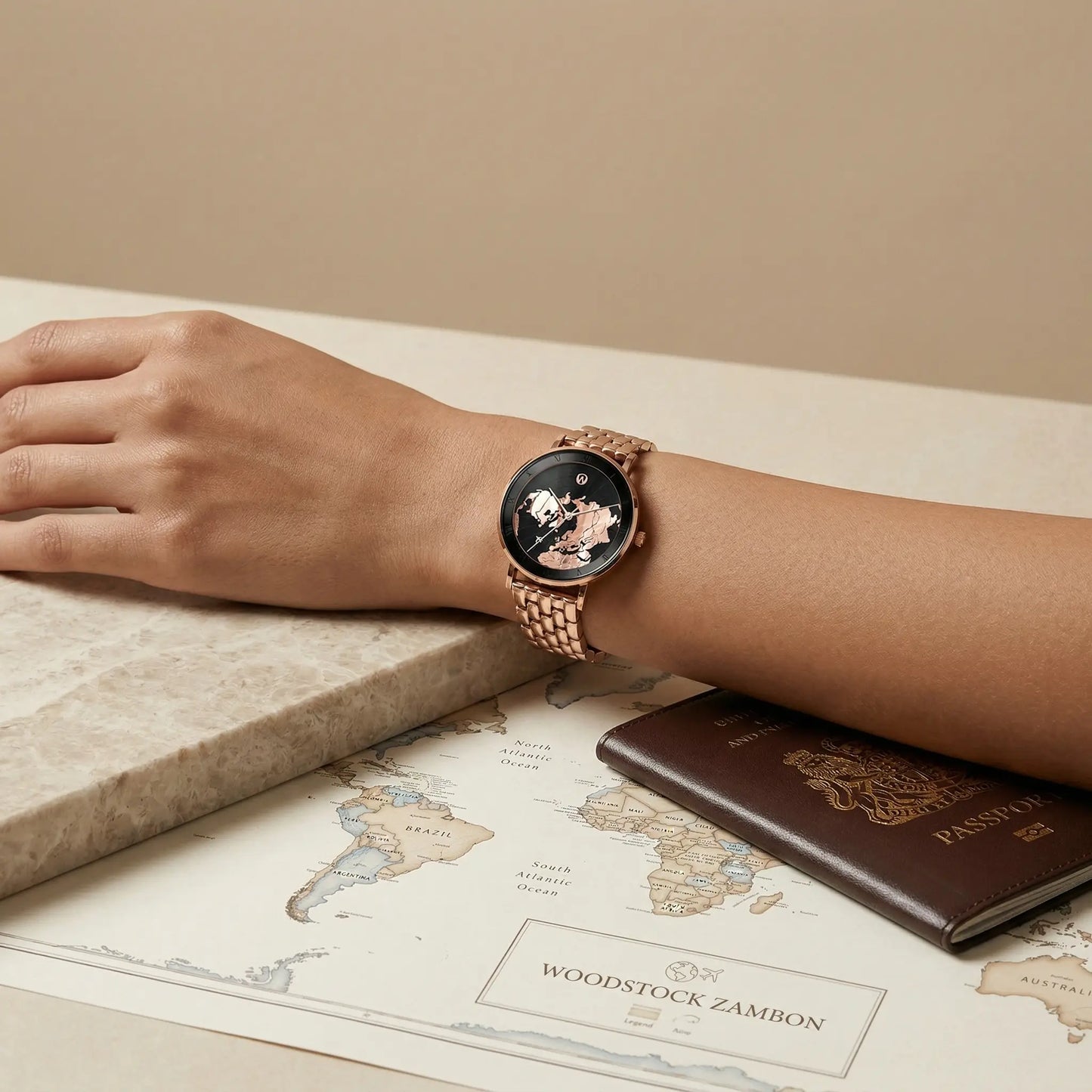 Black world map watch with rose gold details by Woodstock Zambon worn on wrist with passport and vintage map