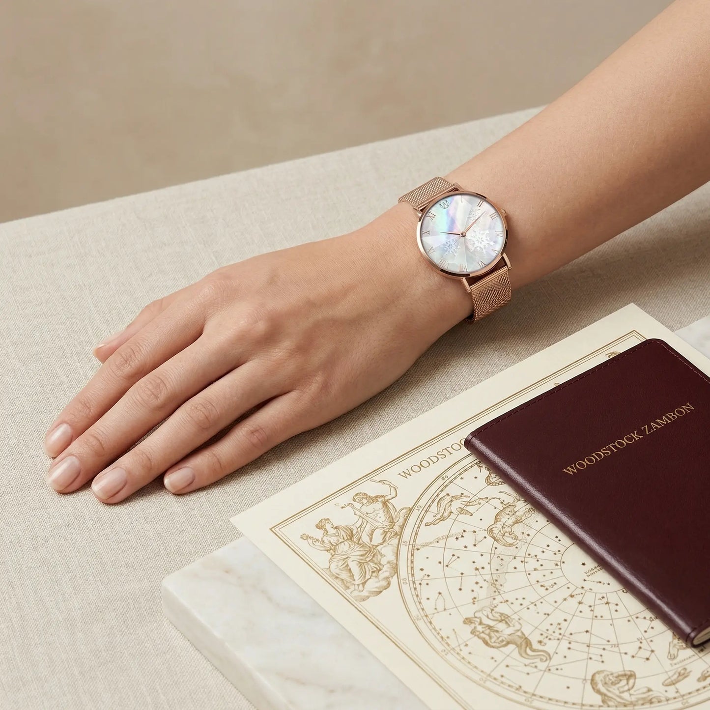 Women's rose gold mother of pearl snowflake watch Woodstock Zambon with diamond effect glass, styled on wrist with travel accessories