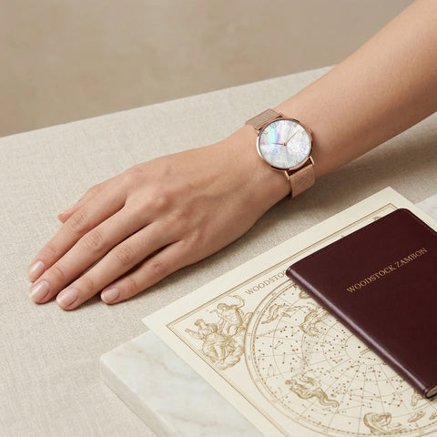 Women's rose gold mother of pearl snowflake watch Woodstock Zambon with diamond effect glass, styled on wrist with travel accessories