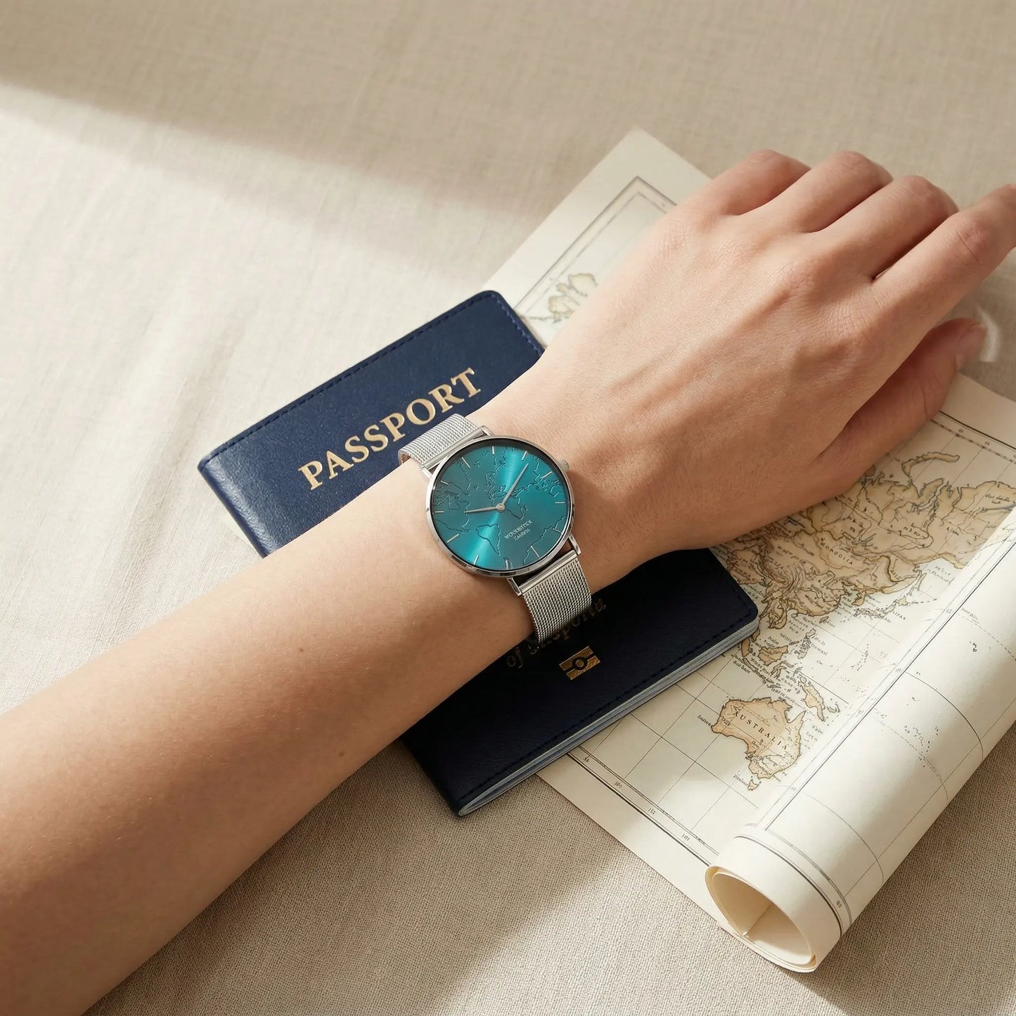 Women's waterproof watch with turquoise reflective world map dial Woodstock Zambon worn on wrist over passport and map